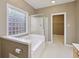 Bright bathroom with a soaking tub, glass block window, and walk-in closet with neutral color palette at 400 S Prairie Trce, Muncie, IN 47304
