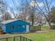 Shows a blue detached garage in the backyard with lawn space, fencing, and trash receptacles at 5006 W Naomi St, Indianapolis, IN 46241