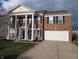 Traditional two-story brick home with white columns, two-car garage, and manicured front lawn at 5565 Noble Dr, Indianapolis, IN 46234