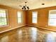 Spacious bedroom with hardwood floors, decorative light fixture, three windows and orange textured wallpaper at 7180 N State Road 42, Eminence, IN 46125