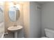 Cozy half bathroom with a pedestal sink, a round mirror, and a toilet, designed for guests at 7247 Barker St, Carmel, IN 46033