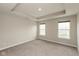 Well-lit bedroom with a tray ceiling, neutral walls, plush carpeting, and two windows allowing natural light at 7247 Barker St, Carmel, IN 46033