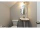 Cozy half bathroom featuring a pedestal sink, toilet, and a round mirror with a modern light fixture at 7247 Barker St, Carmel, IN 46033