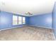 Large room featuring neutral carpet, blue walls, a modern ceiling fan, and natural light from the many windows at 836 Grassy Branch Dr, Indianapolis, IN 46239