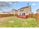 Home backyard featuring a red deck, wood fence, and mature tree at 8808 Hosta Way, Indianapolis, IN 46113