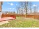A fenced backyard features a red deck, a grassy area, and sparse trees at 8808 Hosta Way, Indianapolis, IN 46113