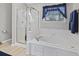 Bathroom featuring a glass-enclosed shower and a white soaking tub beneath a window with blue curtains at 894 Woodgate Ln, Greenwood, IN 46143