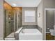 Elegant bathroom showcasing a glass shower, soaking tub with tile surround, and neutral wall and floor tiles at 9539 Rocky Shore Dr, McCordsville, IN 46055