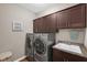 Well-equipped laundry room with front-load washer and dryer, upper cabinets, and a utility sink at 9539 Rocky Shore Dr, McCordsville, IN 46055