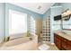 Bright bathroom featuring a separate tub and glass block shower, complemented by a vanity and wall-mounted television at 10844 Fairwoods Dr, Fishers, IN 46037