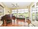 Bright sunroom featuring hardwood floors, comfortable seating, and an elegant baby grand piano at 10844 Fairwoods Dr, Fishers, IN 46037