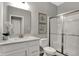 A white bathroom with glass shower, vanity with sink, and a toilet with silver fixtures at 11599 Aubrey Ln, Fishers, IN 46040