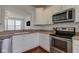 Kitchen with stainless steel appliances, white cabinets, and wood floors, open to the living room at 12683 White Chapel Cir, Fishers, IN 46037