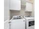 Bright laundry room with modern, white washer and dryer units, and cabinet storage above at 15391 Mystic Rock Dr, Carmel, IN 46033