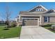 A two-car garage is framed by fresh landscaping and verdant green grass under a brilliant blue sky at 17346 Haxby Ln, Westfield, IN 46074