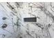 Close-up of shower featuring marble walls, black herringbone tile floor, and overhead and handheld shower fixtures at 2053 Columbia Ave, Indianapolis, IN 46202