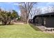 Wide shot of backyard featuring an all-black house, a stone bench, and a grassy lawn at 24 Thornhurst Dr, Carmel, IN 46032