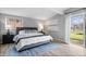 Bright main bedroom with wood floors, large window, and sliding door access to the back yard at 24 Thornhurst Dr, Carmel, IN 46032