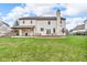 Spacious backyard with a well-maintained lawn, deck, covered patio, and mature trees under a blue sky at 250 W Tansey Crossing, Westfield, IN 46074