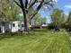 Expansive backyard featuring a large tree, lush lawn, wooden picnic table, and a charming garden at 2843 Canterbury Ln, Indianapolis, IN 46220