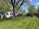 Expansive backyard featuring a large tree, lush lawn, wooden picnic table, and a charming garden at 2843 Canterbury Ln, Indianapolis, IN 46220