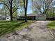 Cozy single-Gathering home featuring a paved driveway leading to an attached garage and lush greenery at 2843 Canterbury Ln, Indianapolis, IN 46220
