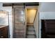 View of carpeted stairs adjacent to sliding barn door with vintage lamp at 2909 Huntsville Rd, Pendleton, IN 46064