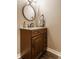 Powder room featuring a dark wood vanity, marble countertop, and round mirror with decorative accents at 311 2Nd Ne St, Carmel, IN 46032