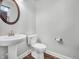 This powder room features a pedestal sink, round mirror, and wood-look flooring at 317 Alden Way, Carmel, IN 46032