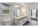 Bright bathroom featuring double vanity with marble countertop and stylish white cabinets with black hardware at 3244 Devereaux Dr, Indianapolis, IN 46228