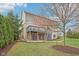 Backyard view of the house with a wooden deck, stone patio, and beautifully landscaped yard at 3892 Pelham Rd, Carmel, IN 46074