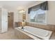 Large bathroom featuring a soaking tub, window, cabinet and a doorway leading into an additional space at 3892 Pelham Rd, Carmel, IN 46074