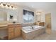 Spacious Primary bathroom featuring a soaking tub with tile surround, separate vanities, and a large window at 3892 Pelham Rd, Carmel, IN 46074
