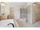 Bright bathroom featuring a soaking tub, glass enclosed shower, neutral tile, and access to the walk-in closet at 3892 Pelham Rd, Carmel, IN 46074
