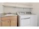Bright laundry room features a wash sink with granite countertop, storage cabinet, and a modern white washer and dryer at 3892 Pelham Rd, Carmel, IN 46074