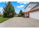 Long concrete driveway with mature trees and lawn leading to a three-car garage at 6110 Tanana Dr, Carmel, IN 46033