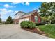 Brick home featuring an attached three-car garage, white trim, and lush landscaping at 6110 Tanana Dr, Carmel, IN 46033