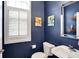 Stylish powder room featuring blue walls, modern fixtures, and a decorative mirror at 6110 Tanana Dr, Carmel, IN 46033