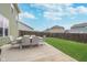 An outdoor patio table set with a six chairs sits on a concrete patio and faces out on the green grass and fenced in yard at 726 Jefferson Park Dr, Pittsboro, IN 46167