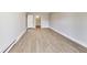 Bright living room features light grey walls and light wood-look flooring with door to another room at 7906 E 21St St, Indianapolis, IN 46219