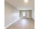 Bright living room features light grey walls and light wood-look flooring with window and white door at 7906 E 21St St, Indianapolis, IN 46219