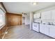 Inviting living space with white kitchen, wood-look flooring, and wood-paneled walls at 7906 E 21St St, Indianapolis, IN 46219