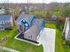 Stunning aerial view of a two-story home with a brick facade, blue accents, and a spacious driveway in a lush, green setting at 8228 Morel Dr, Indianapolis, IN 46256
