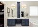 A bathroom vanity with double sinks, navy cabinets, gold hardware, and gold light fixtures at 8228 Morel Dr, Indianapolis, IN 46256
