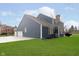 Back exterior of house with blue siding, white trim, a big yard and a three car garage at 8228 Morel Dr, Indianapolis, IN 46256