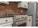 A stainless steel range against exposed brick is surrounded by gray cabinets and stainless refrigerator at 8228 Morel Dr, Indianapolis, IN 46256