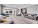 Open-concept living area with gray sofas, wood-look flooring, and access to kitchen and staircase at 8610 Fawn Way, McCordsville, IN 46055