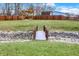 Scenic backyard with a small wooden bridge over a rock-lined creek, framed by a manicured lawn and wooden fence at 9255 W 30Th St, Indianapolis, IN 46234