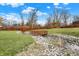 Expansive backyard view featuring a charming wooden bridge, a pergola, and a creek, surrounded by lush green grass at 9255 W 30Th St, Indianapolis, IN 46234