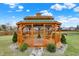 Wooden gazebo with green roof and accents, situated in a landscaped yard featuring decorative stone and manicured shrubs at 9255 W 30Th St, Indianapolis, IN 46234